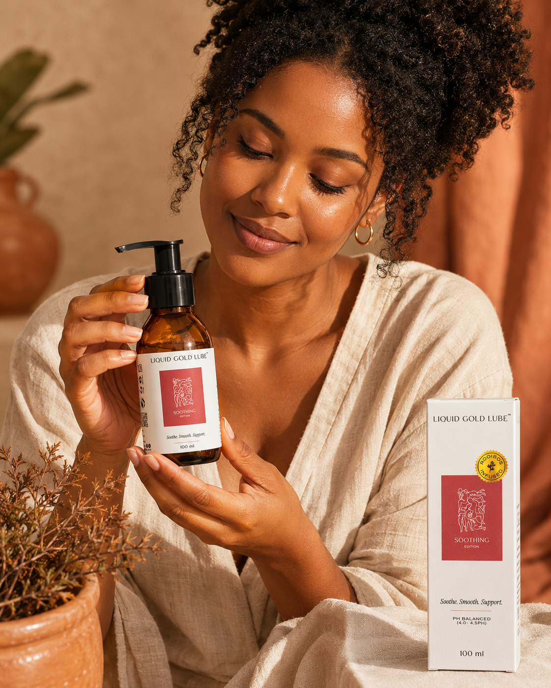 AI-generated Meta ad image for LiquidGold's Soothing Edition — lifestyle creative. A South African woman in a cream linen wrap in a warm terracotta-toned space, holding the amber glass bottle. Generated with ChatGPT image generation during the 19 May 2026 session.