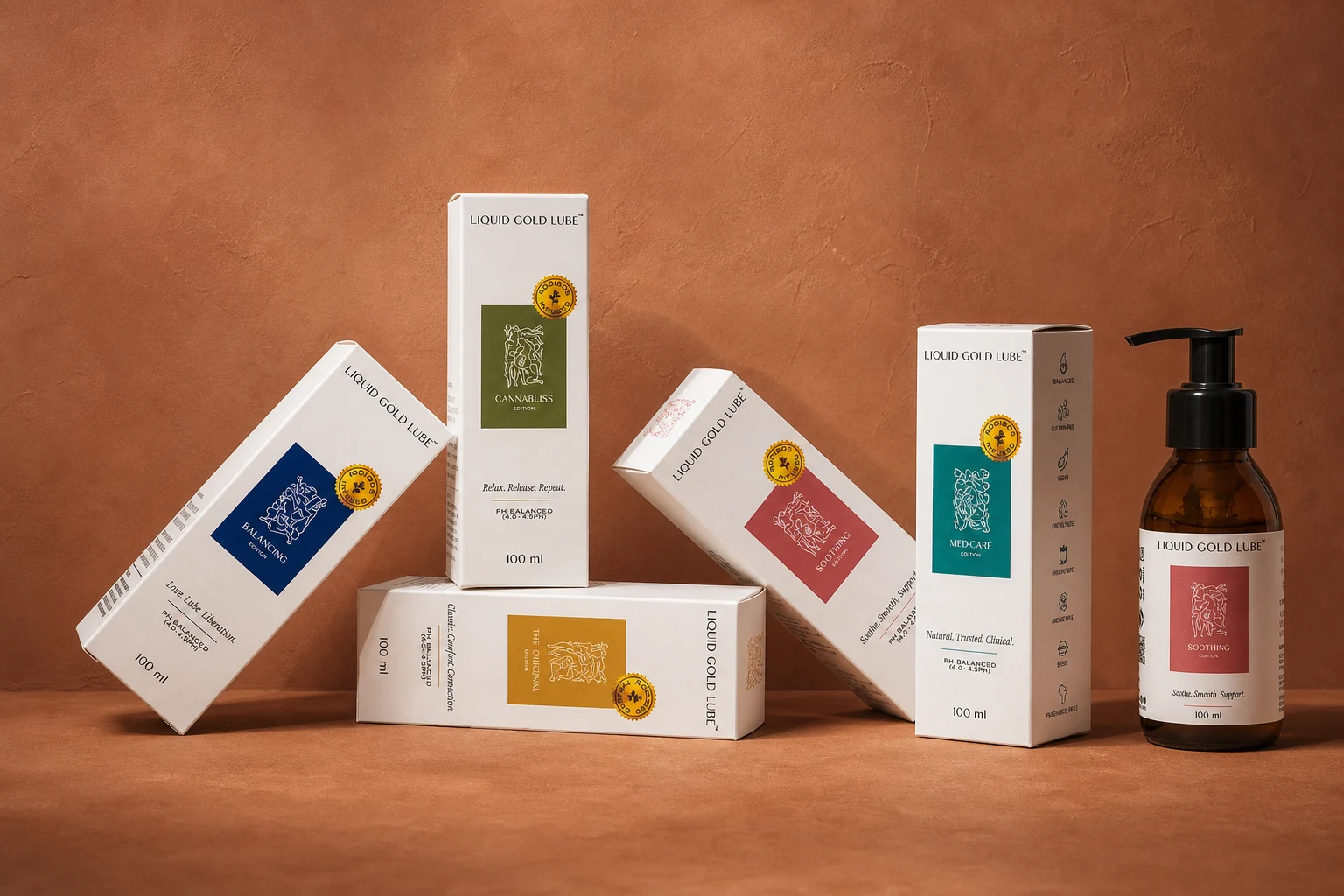The full LiquidGold Lube range — five product boxes and an amber glass bottle arranged on a warm terracotta surface: Balancing Edition, Cannabliss, The Original, Soothing Edition, and Med-Care. Made in Cape Town.