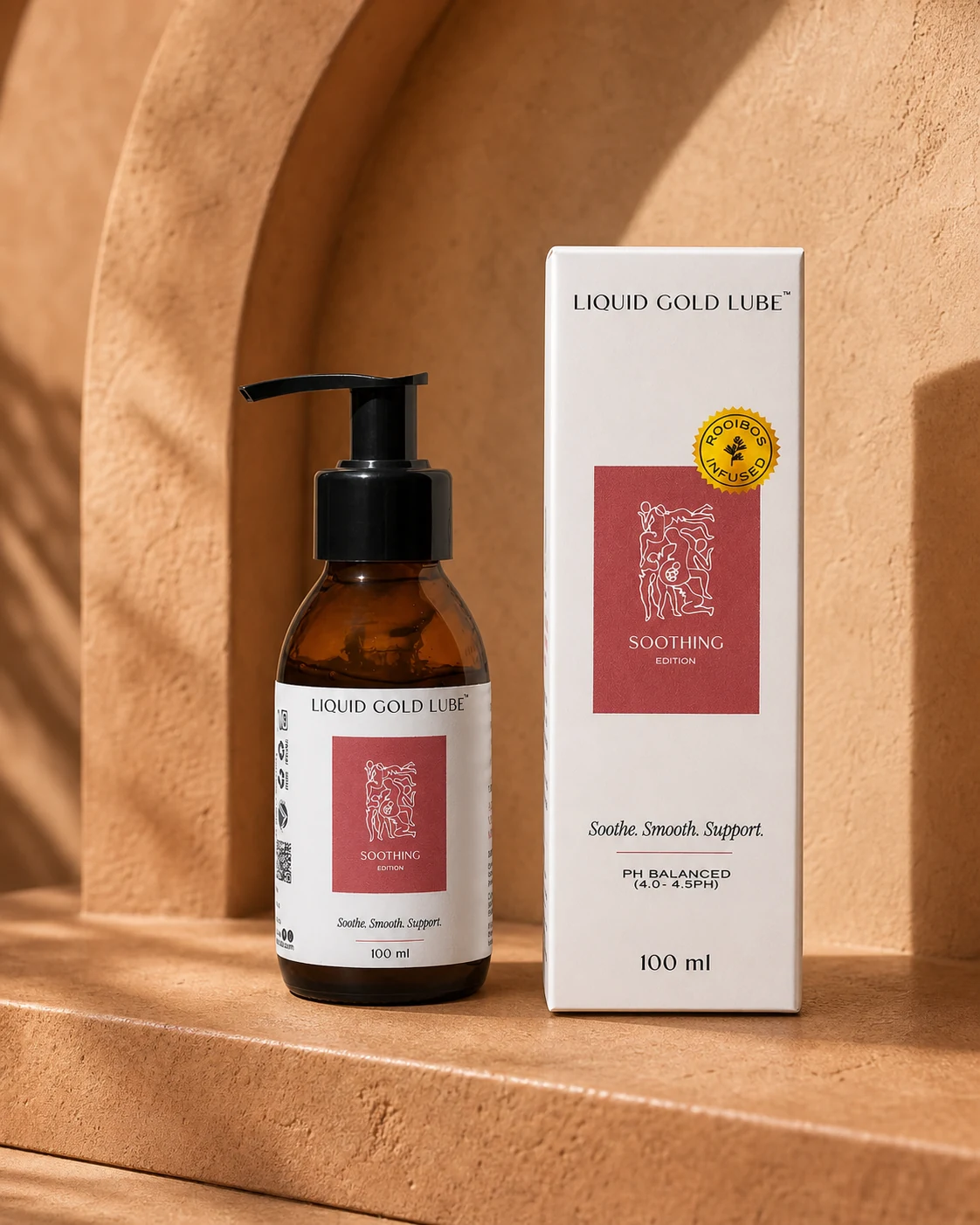 The Soothing Edition by LiquidGold — amber glass pump bottle beside its packaging box on a warm terracotta surface with arch shadows. Rooibos-infused intimate lubricant, made in Cape Town.
